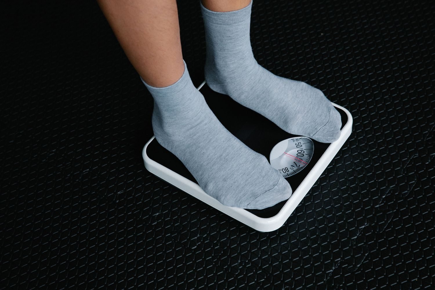 Person stepping on a bathroom scale in the morning as part of a weight maintenance routine