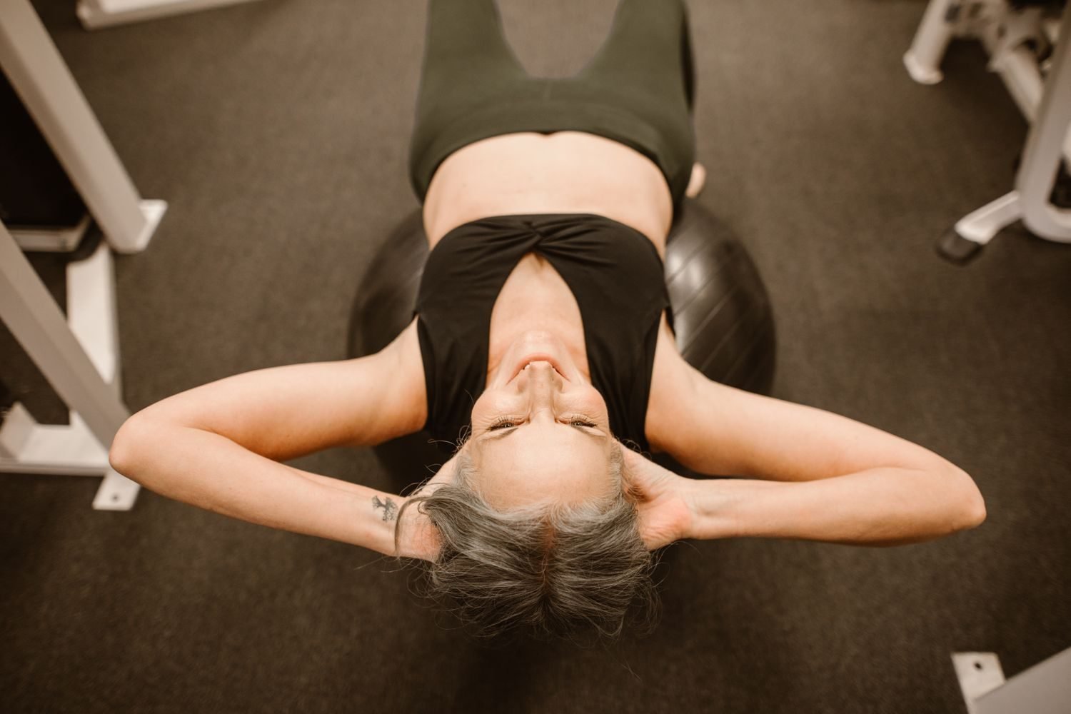 Middle-aged woman performing a resistance training exercise with dumbbells in a gym setting