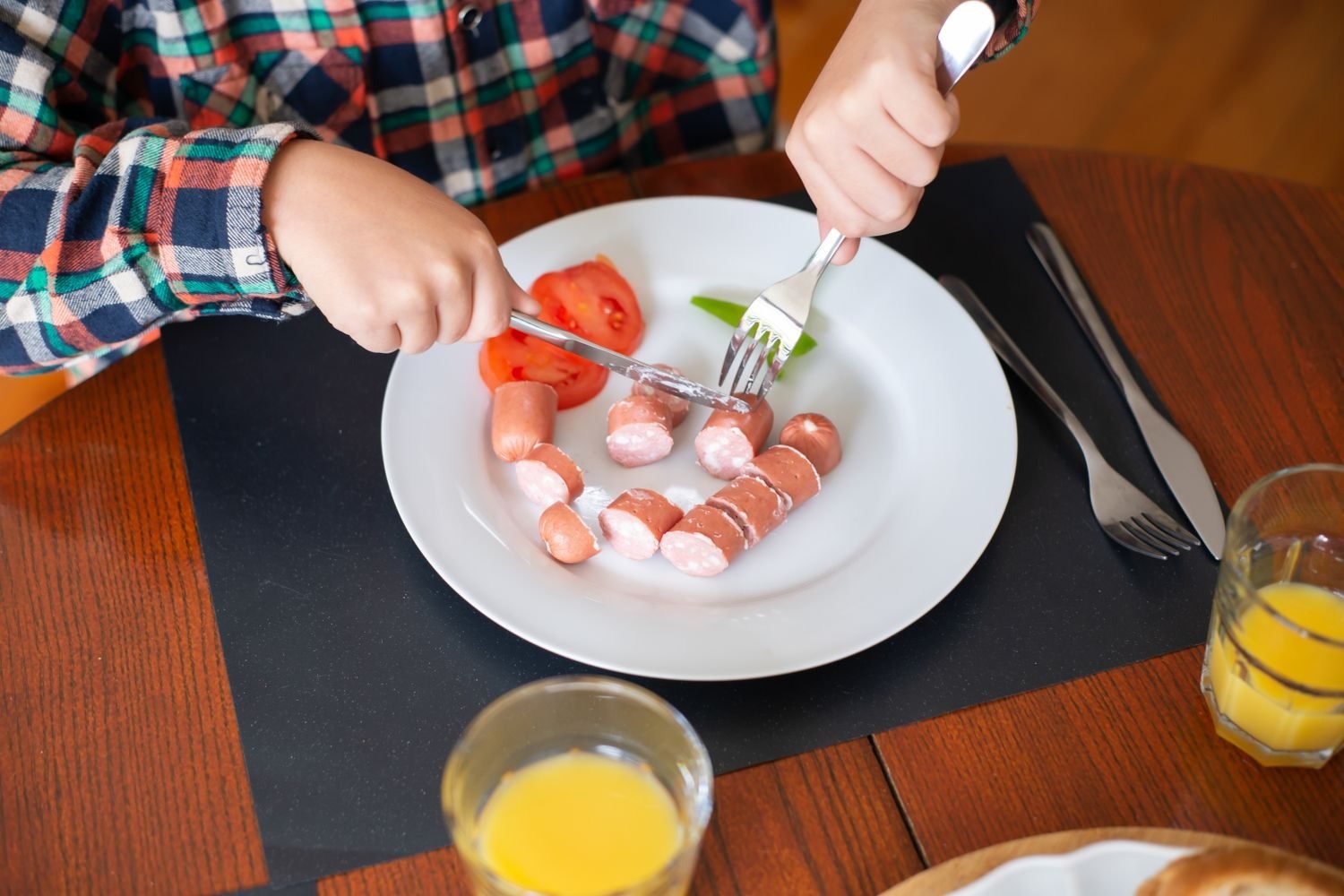 Young child eating a balanced plate of vegetables, protein, and grains at a family table