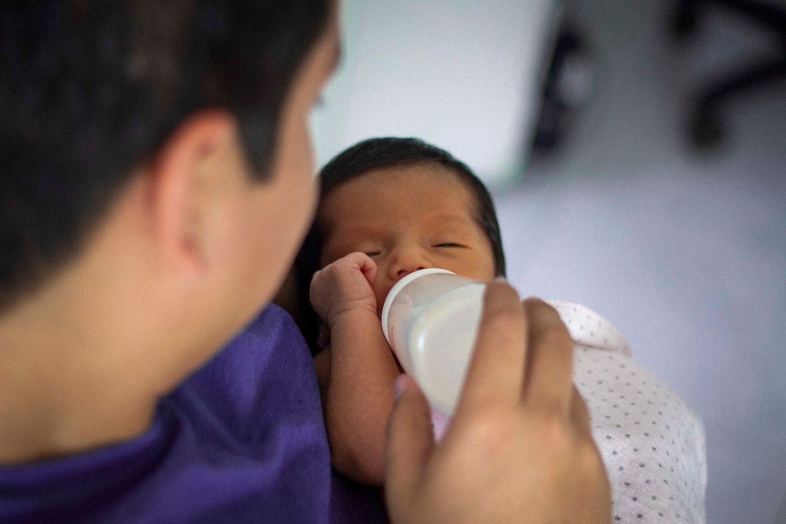 Parent bottle-feeding a newborn infant during the exclusive milk-feeding stage before 6 months