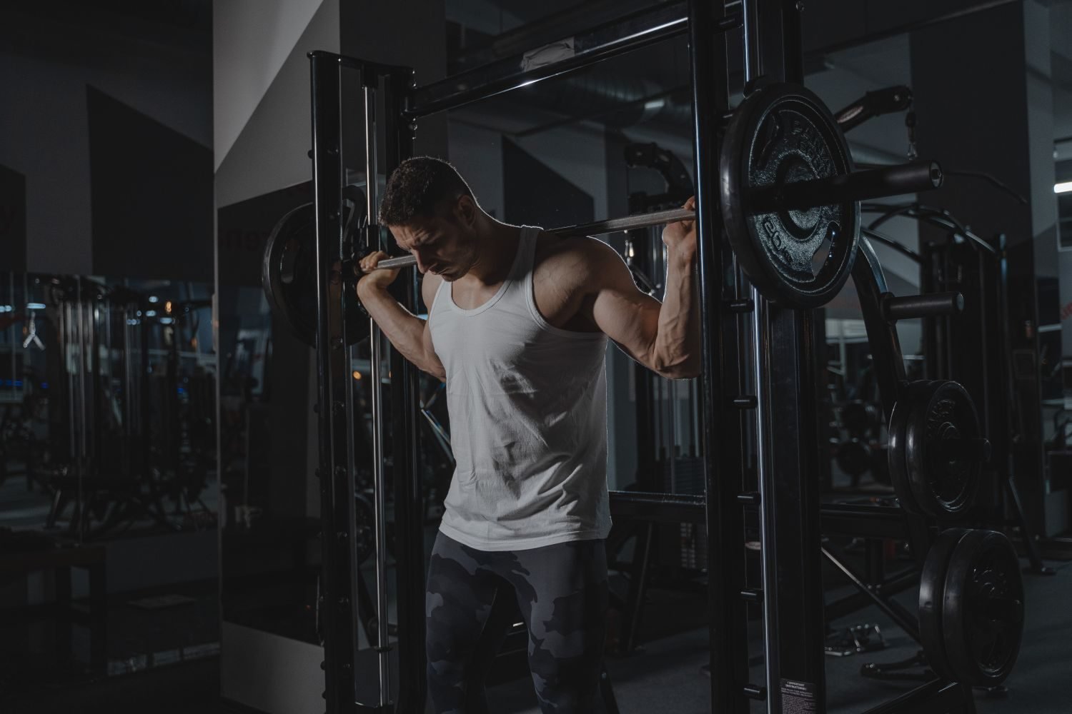 Man performing a barbell squat on a smith machine at the gym