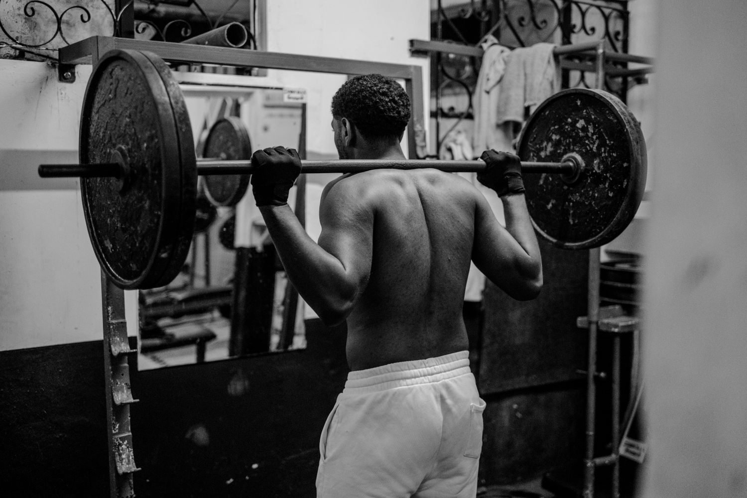 Man performing a barbell back squat at the gym