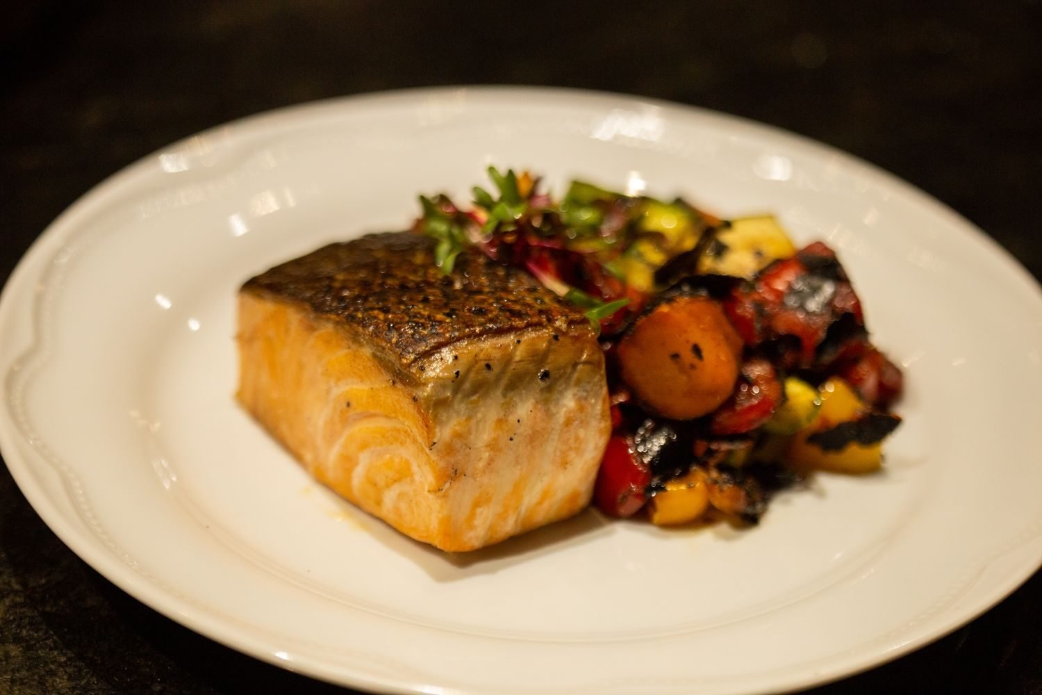 Low sodium meal plate with grilled salmon, roasted vegetables, and fresh herbs instead of salt
