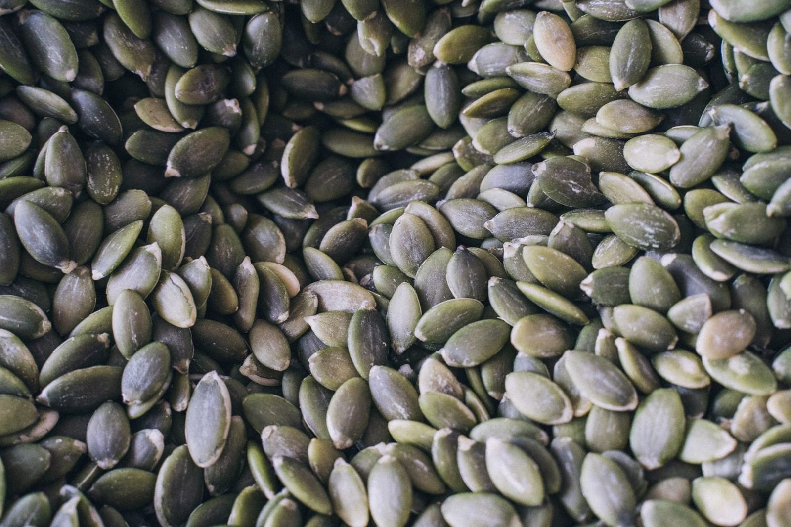 Assortment of magnesium-rich foods including almonds, pumpkin seeds, spinach, and whole grains on a wooden table