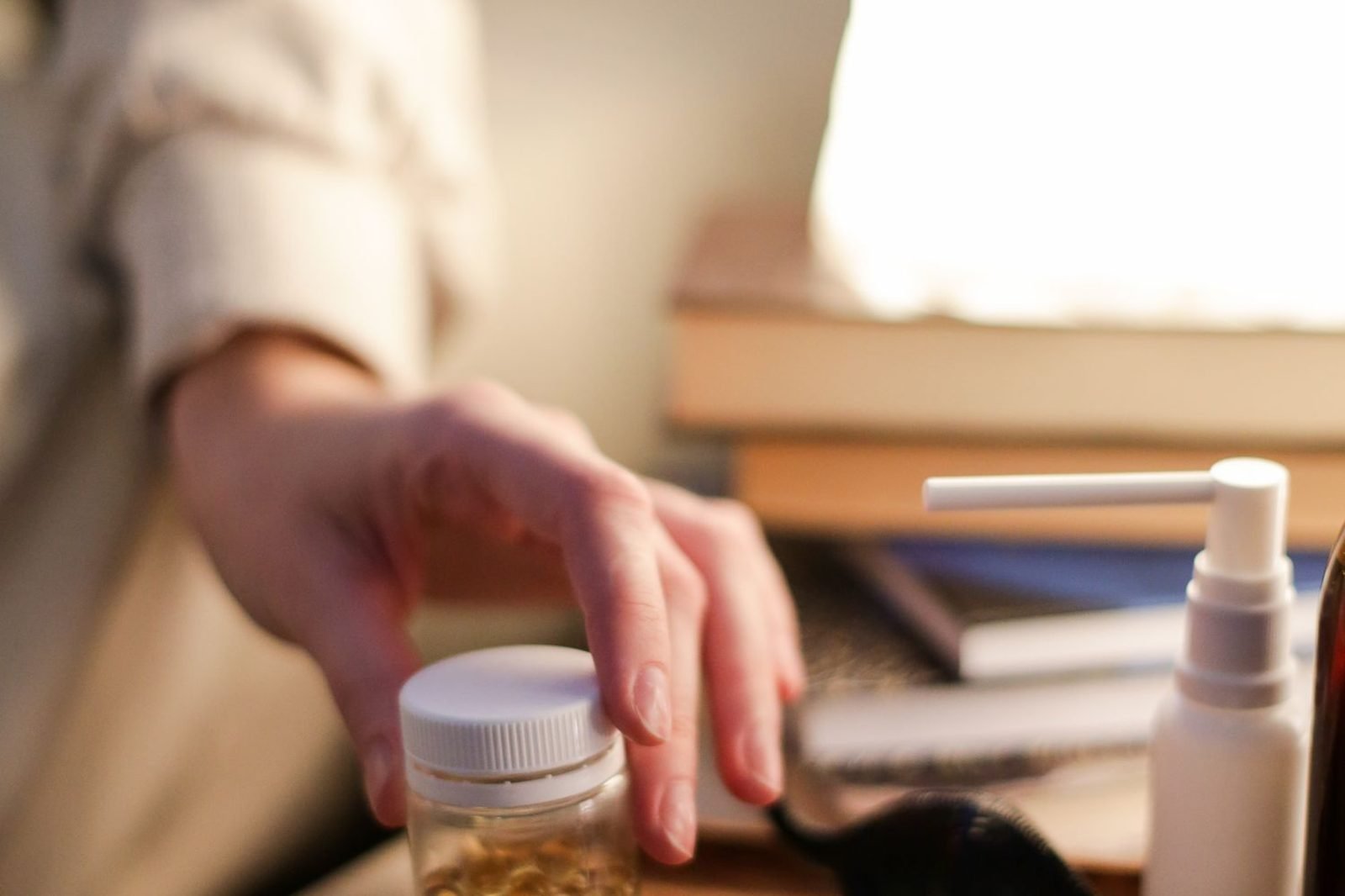 Bottle of magnesium supplement capsules next to a glass of water on a nightstand