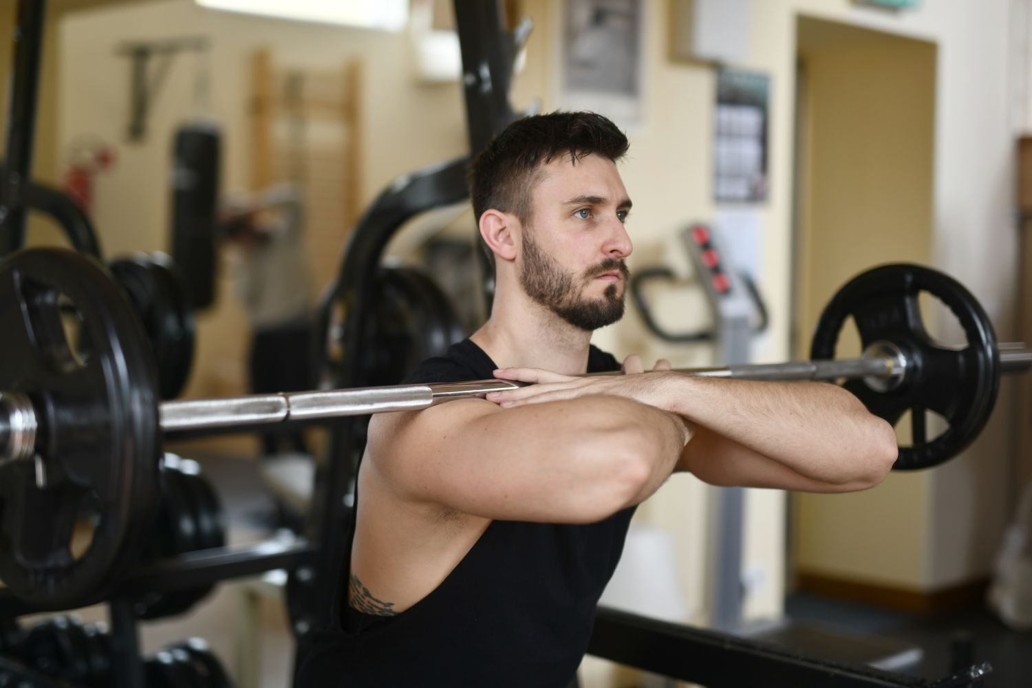 Man performing a front squat with a barbell at the gym