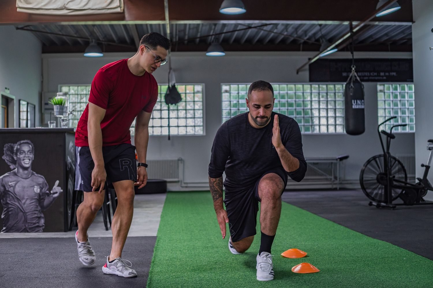 Personal trainer coaching a client through an agility drill in a gym