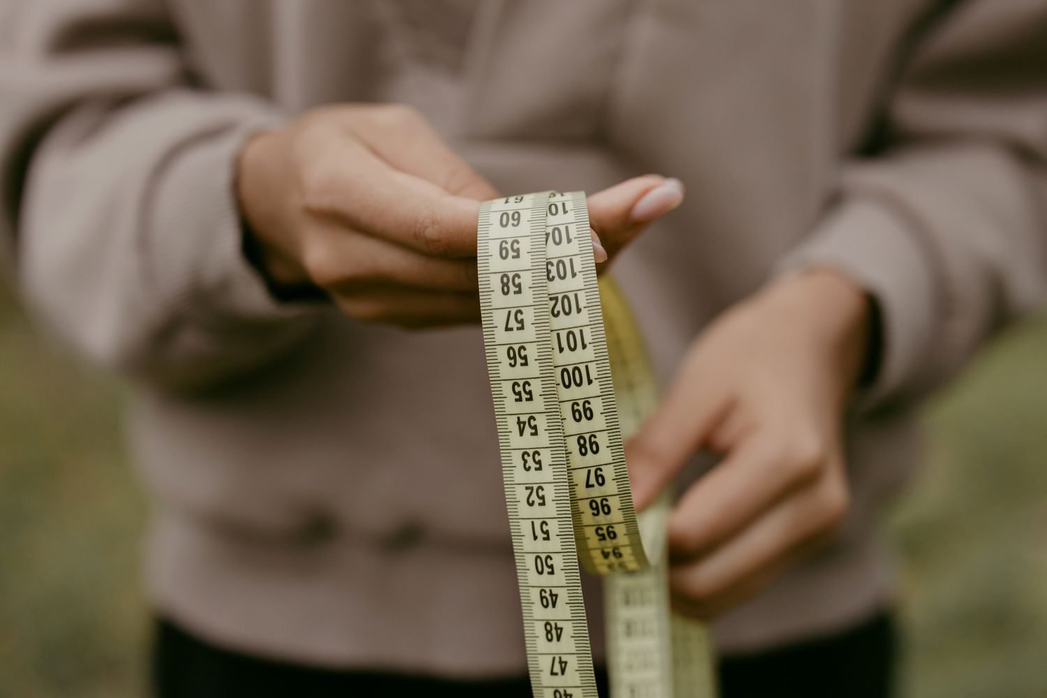 Notebook and calculator showing a step-by-step BMR and TDEE calculation with a scale and measuring tape