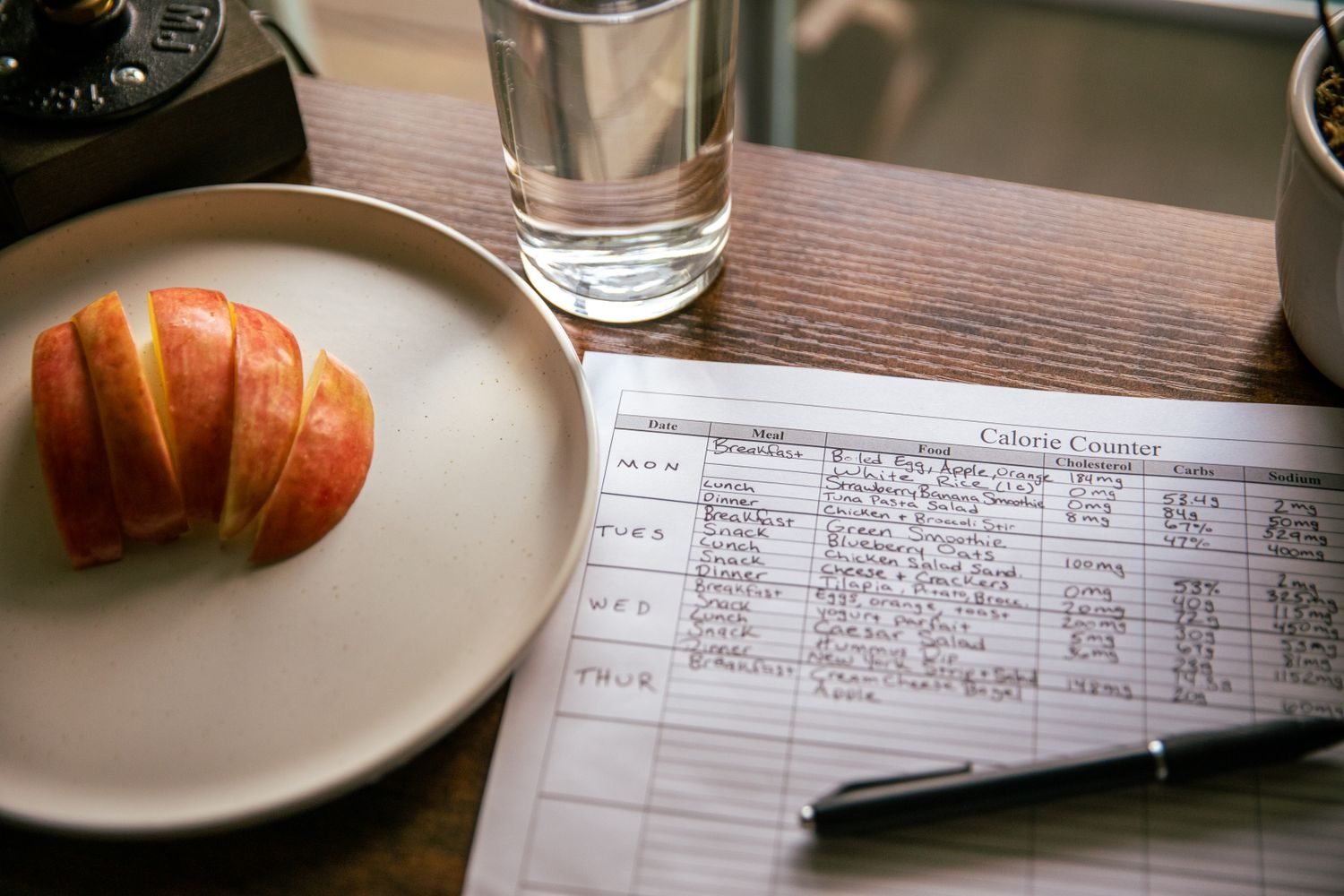 Person reviewing a weekly weight trend chart next to a plate of balanced, portioned food