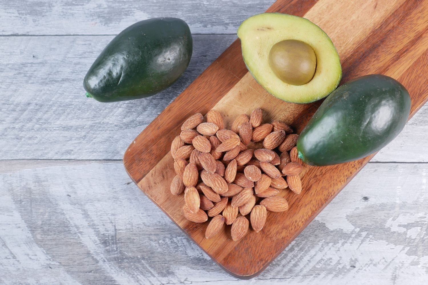 Assortment of healthy fats for weight gain including almonds, walnuts, avocado, and ghee in bowls