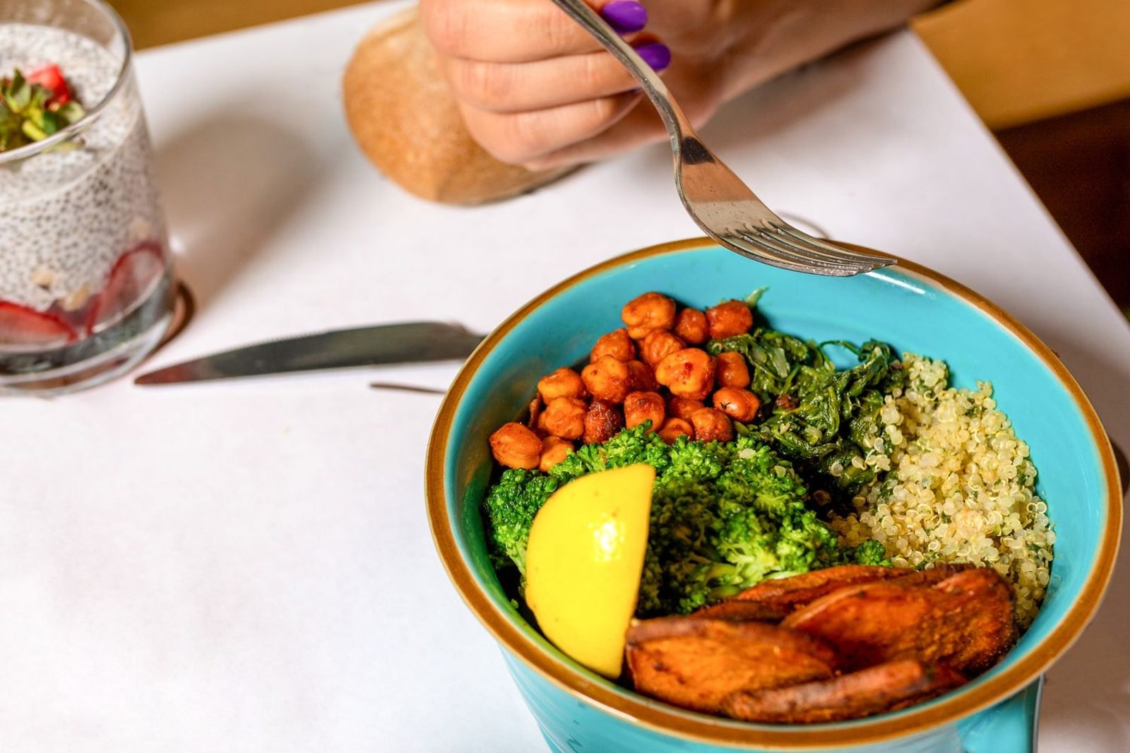 Pregnant woman preparing a balanced meal with vegetables, whole grains, and protein in her kitchen