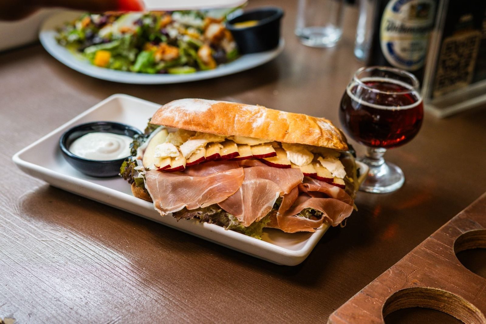 Foods to avoid during pregnancy including raw fish, soft cheese, deli meat, and alcohol crossed out on a kitchen counter