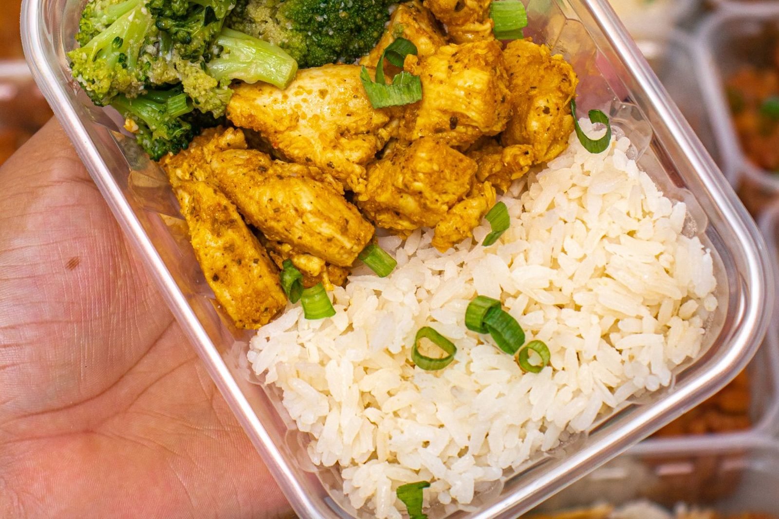 Person meal prepping vegetables and lean protein in kitchen containers for sustainable weight loss nutrition