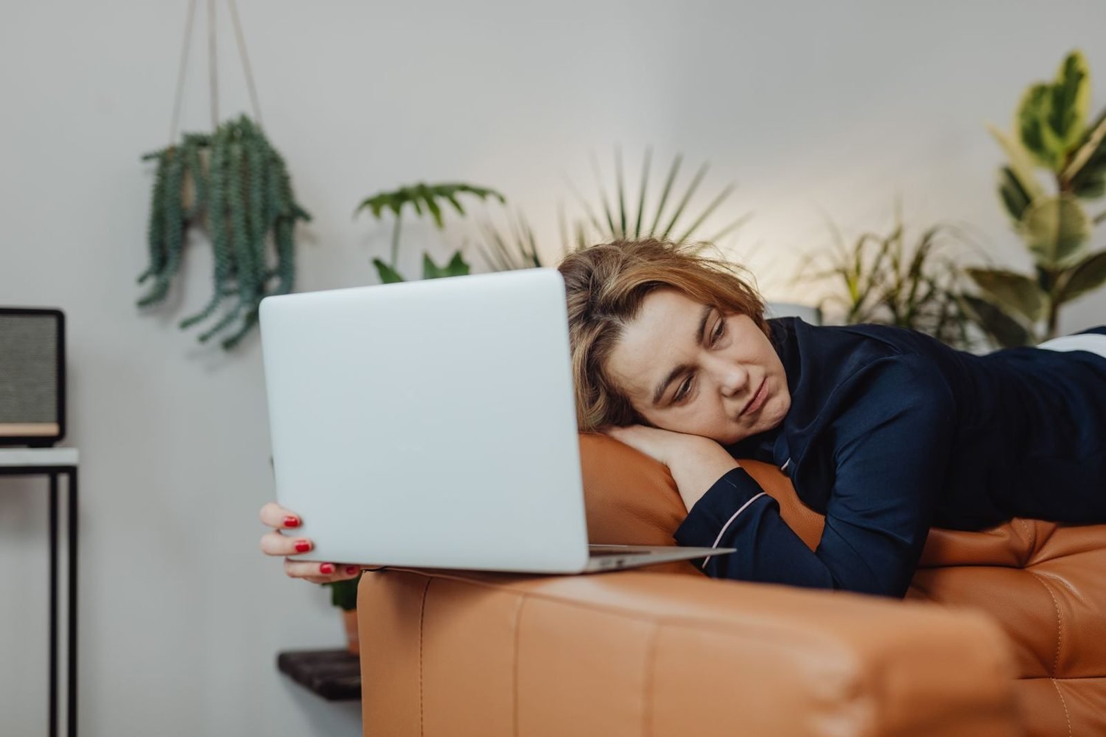 Person looking tired and fatigued, resting head on hand at a desk