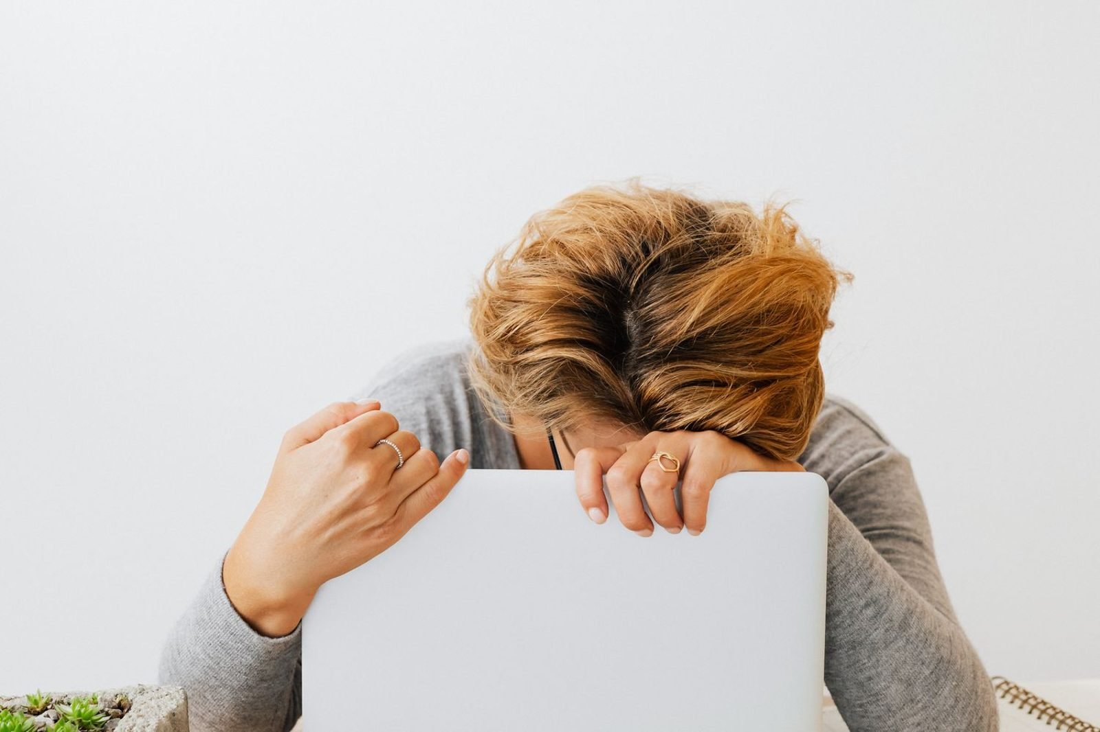 Tired woman rubbing her eyes at a desk, showing signs of nutritional deficiency fatigue