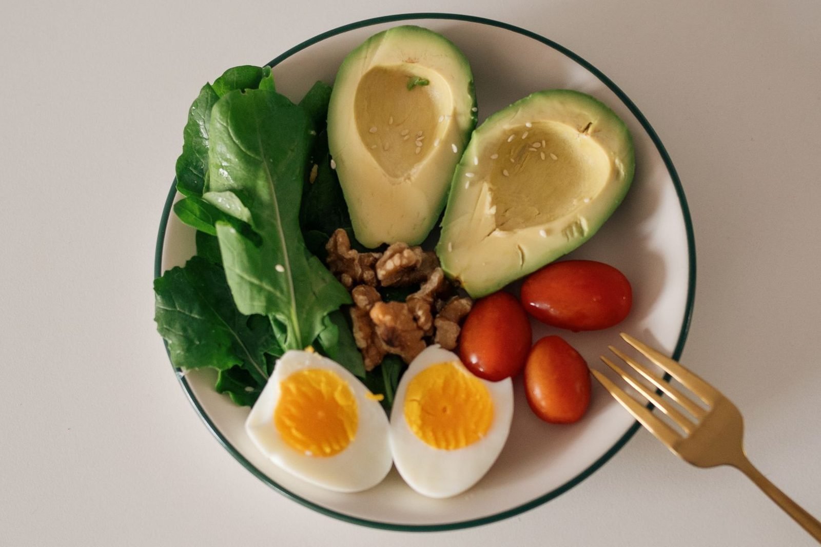 Assortment of nutrient-dense whole foods including leafy greens, citrus fruit, nuts, and lean protein arranged on a table