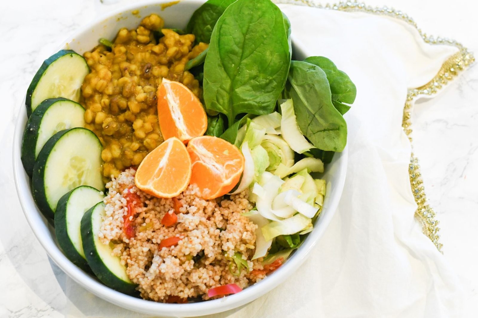 Plate of iron-rich foods including lentils, spinach, lean meat, and citrus segments arranged together