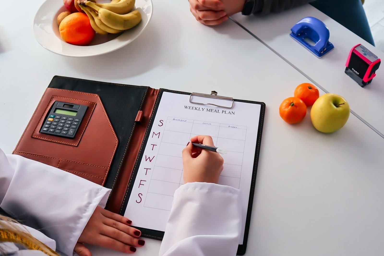 Weekly meal planning notebook with iron-rich foods and a glass of orange juice on a kitchen counter