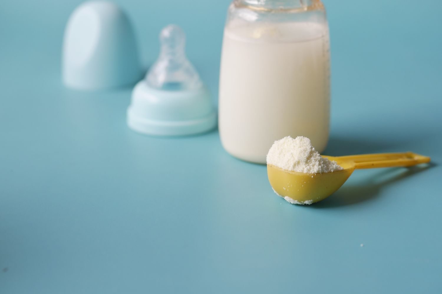 Side-by-side comparison of breast milk and infant formula in bottles with nutrient icons