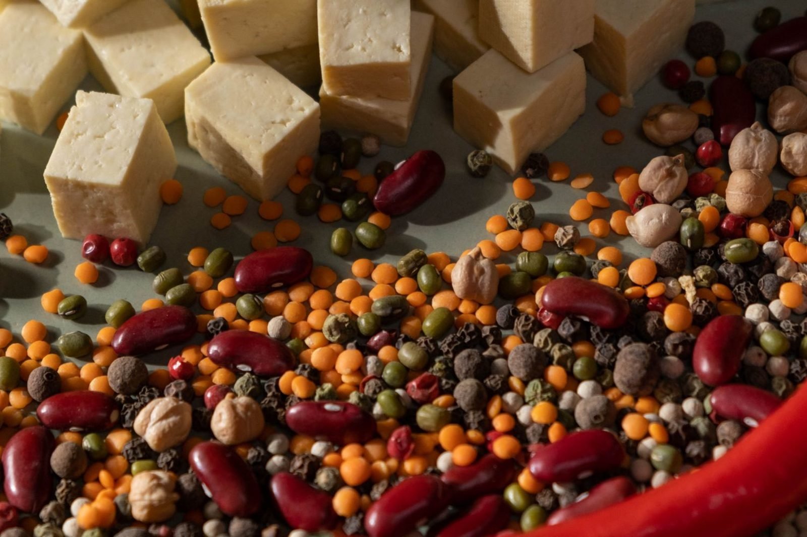 Variety of plant-based protein foods including lentils, chickpeas, quinoa, tofu, nuts, and whole grains