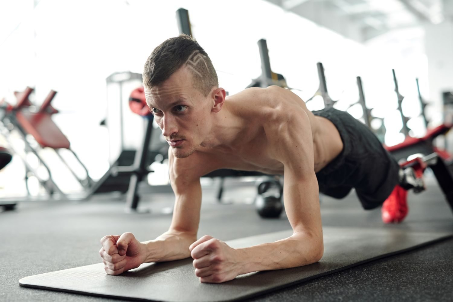 Man holding a forearm plank on a mat in the gym