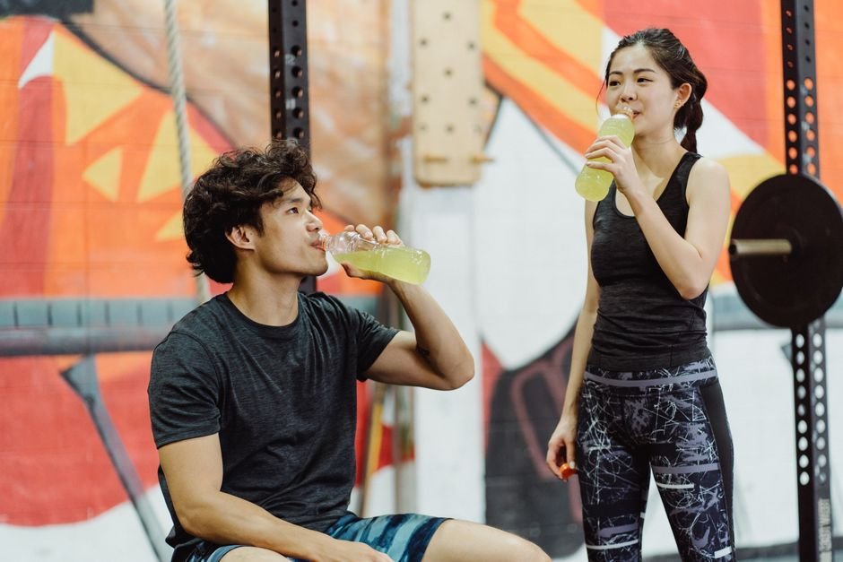 People drinking a pre-workout energy drink at the gym