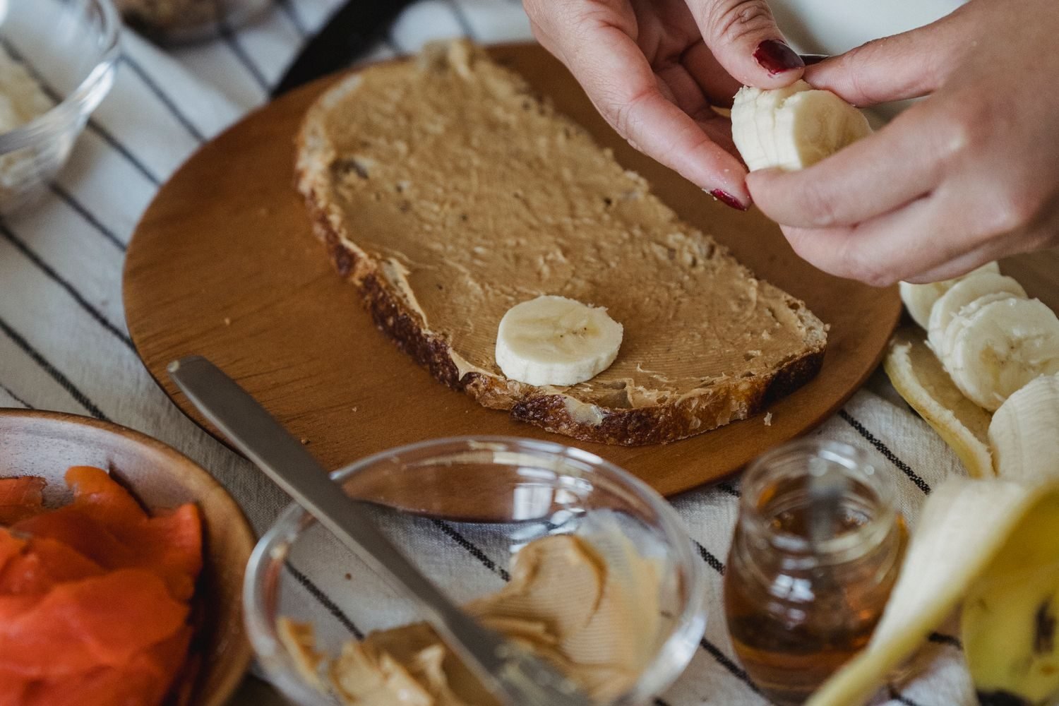 Banana slices being added to peanut butter toast