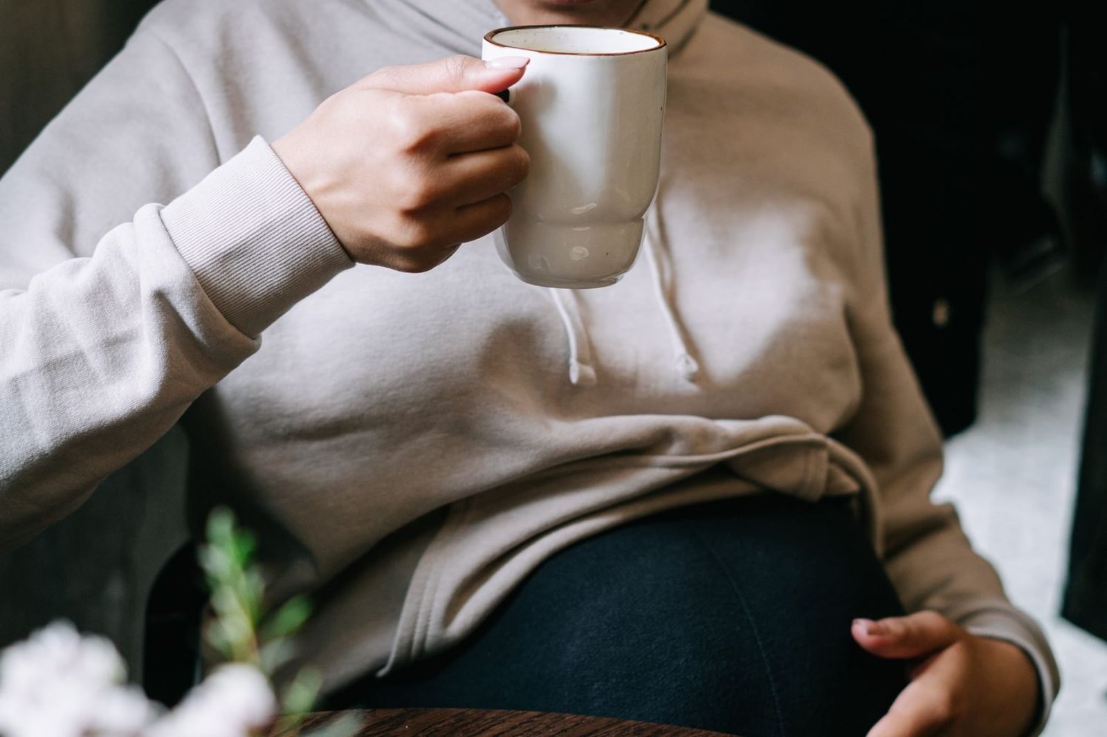 Pregnant woman drinking ginger tea and eating crackers to manage morning sickness nausea