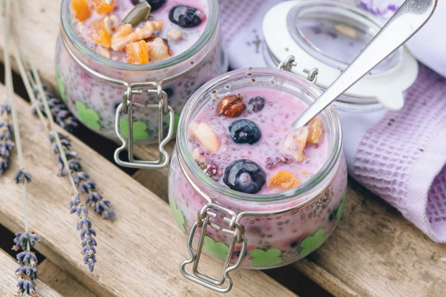 Mason jars of overnight oats topped with berries and chia seeds lined up in a refrigerator