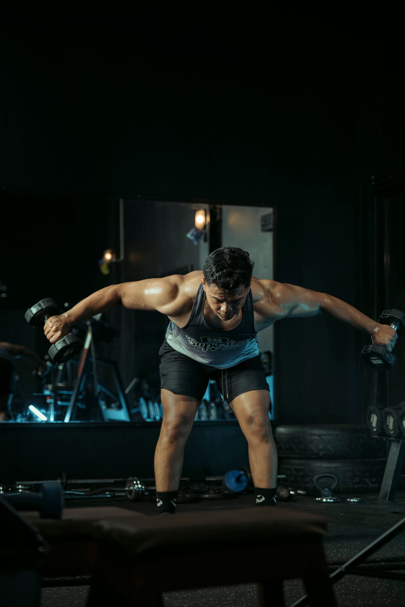 Man performing a bent-over dumbbell reverse fly for the rear delts