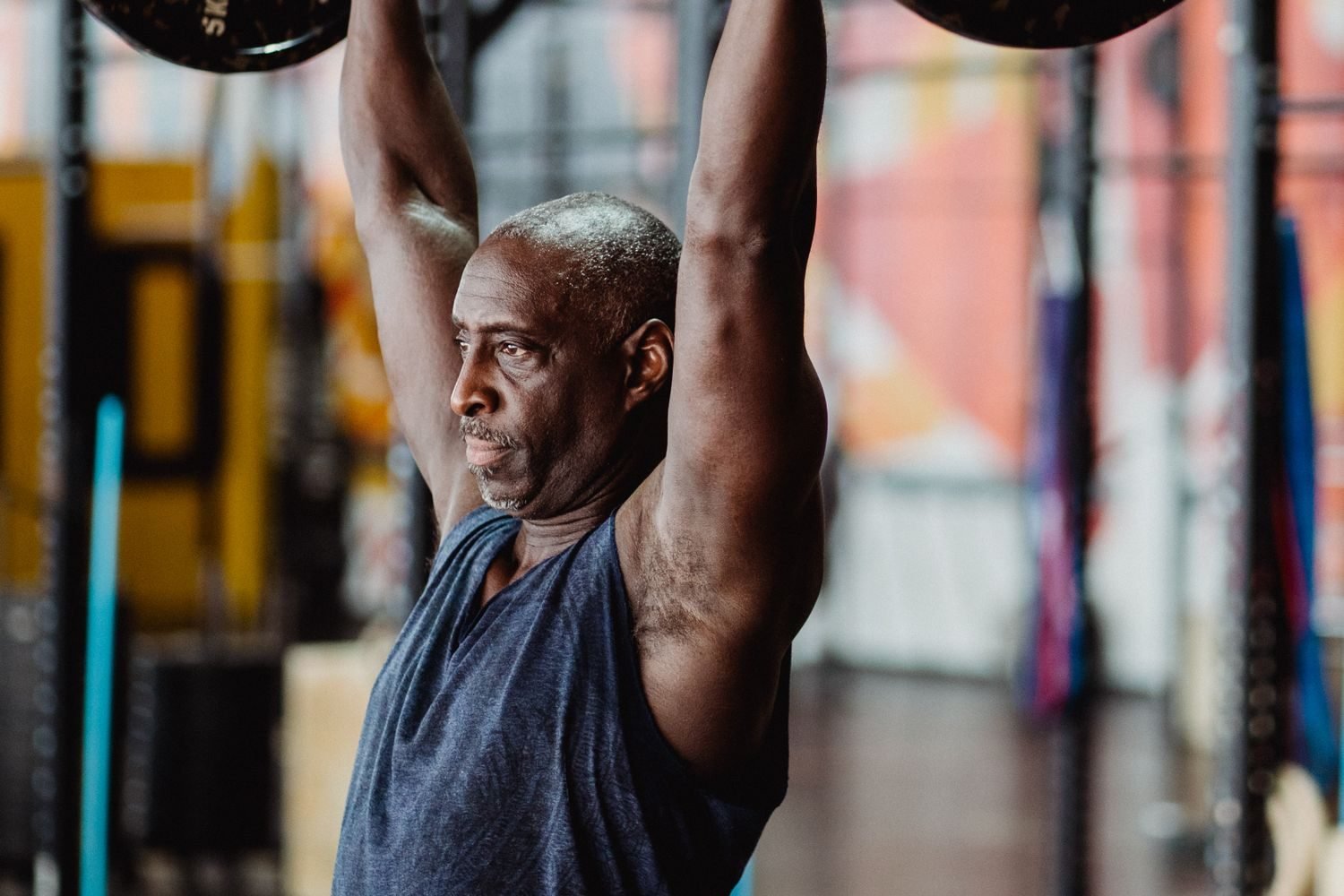 Man performing an overhead barbell press during a shoulder workout