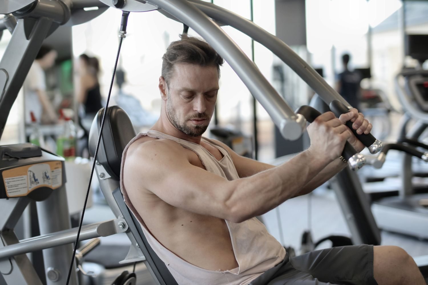 Man performing a shoulder isolation exercise on a cable machine