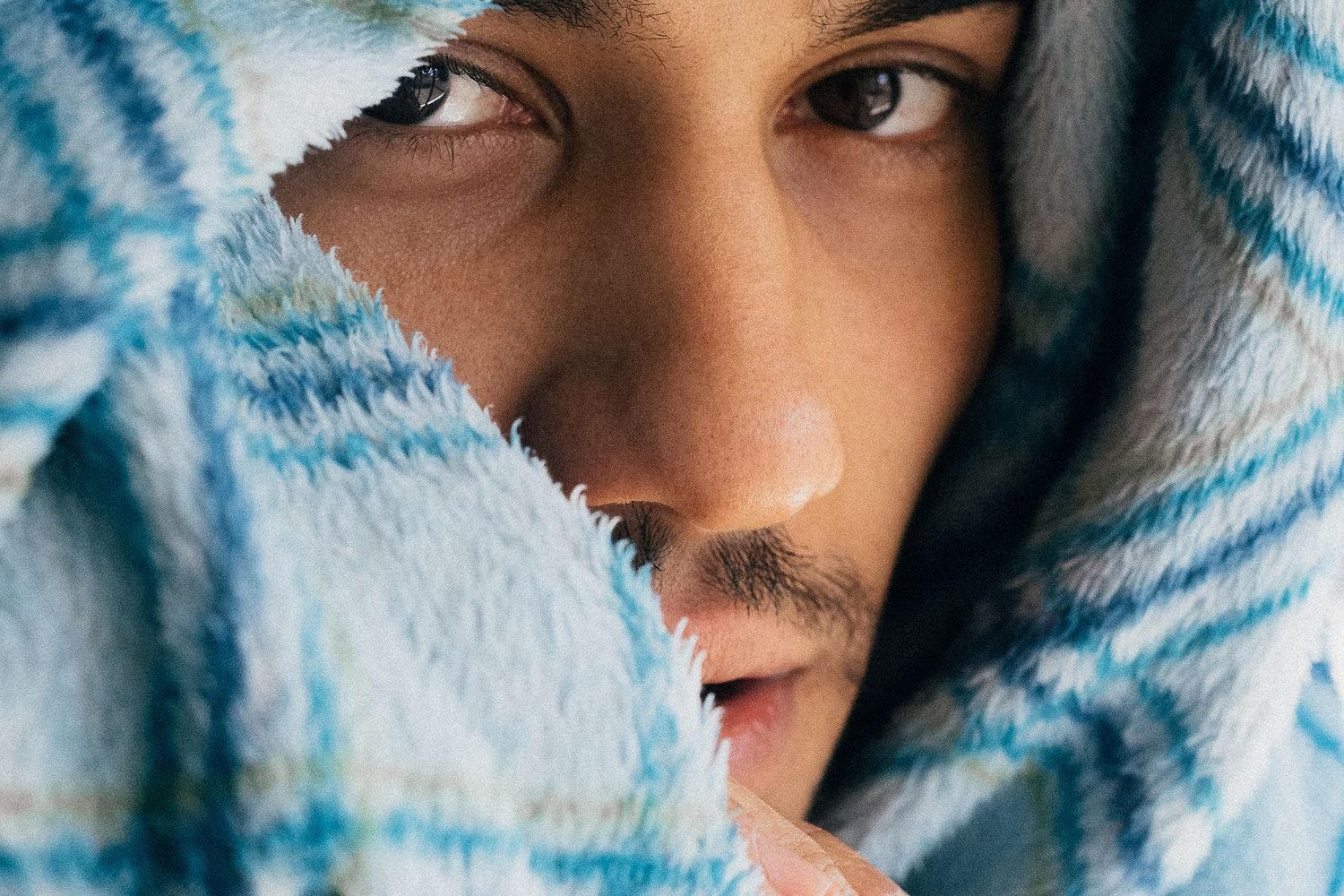 Person wrapped in a blanket feeling cold and fatigued, a common sign of an underactive thyroid