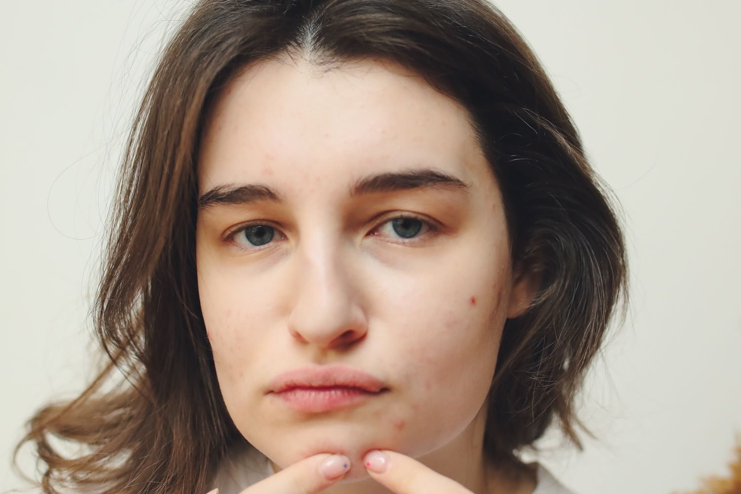 Close-up of a woman examining skin changes on her face in natural light