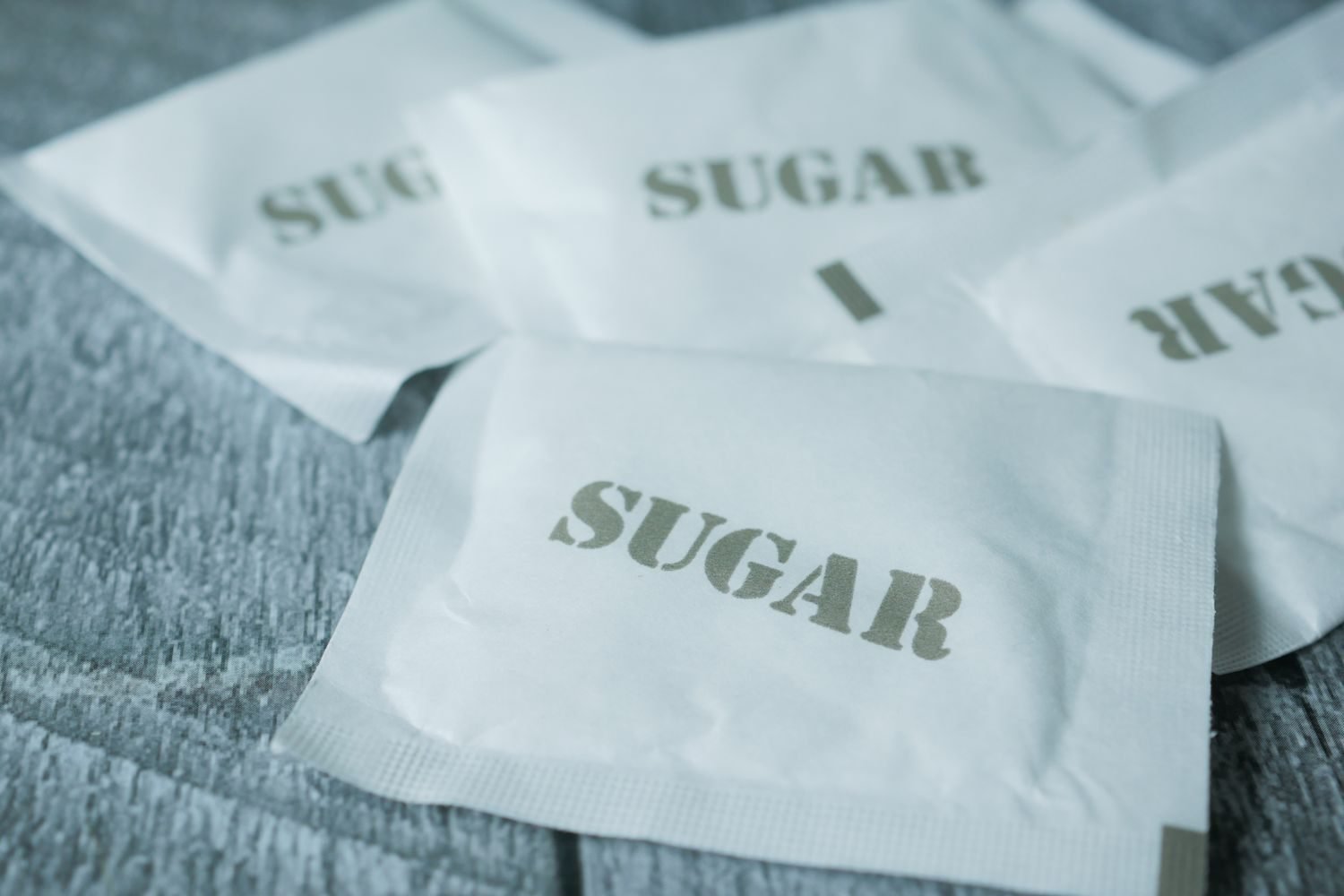 Stevia leaves next to packets of artificial sweetener and a sucralose bottle, illustrating natural versus synthetic sweetener sources