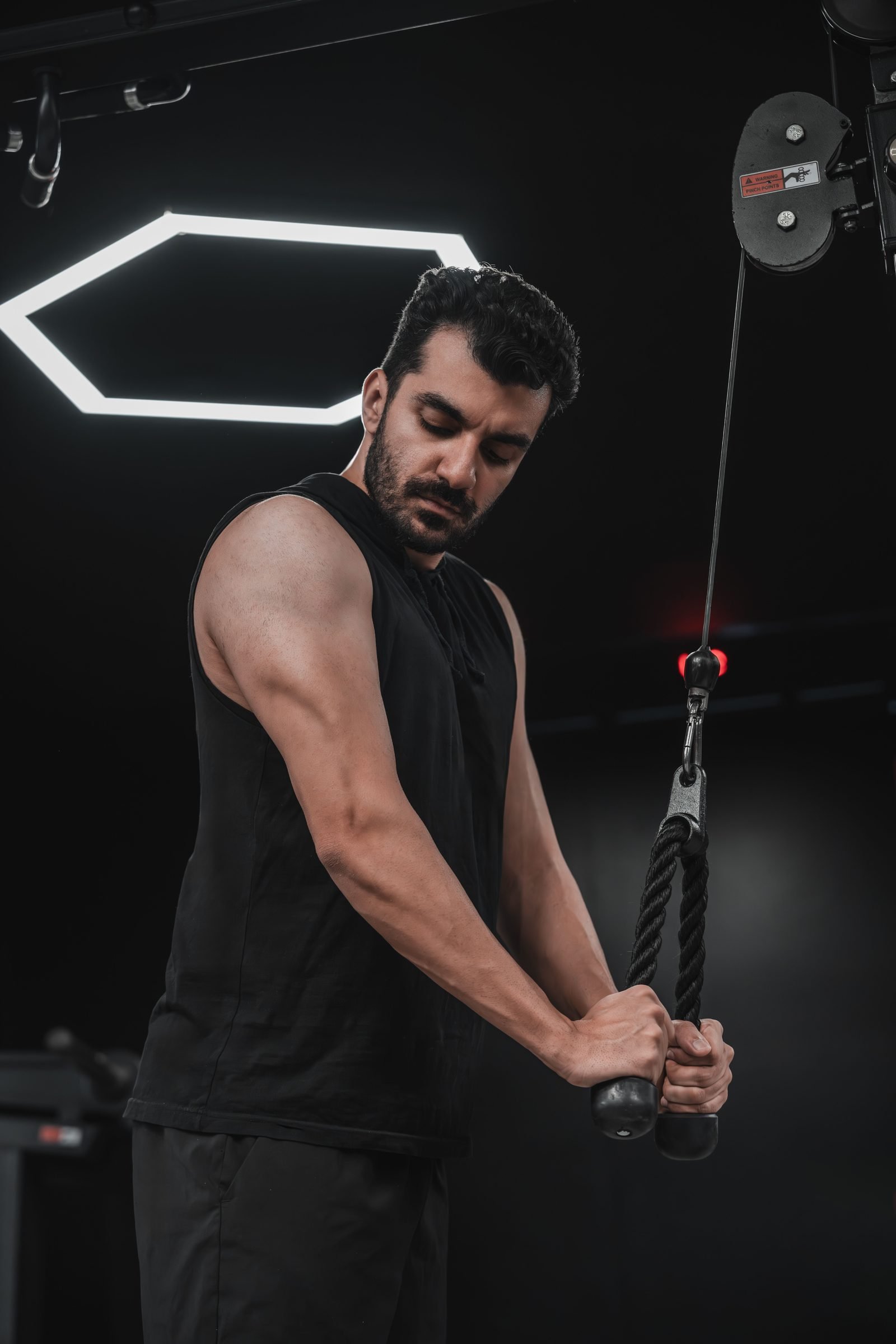 Man performing a cable tricep pushdown with a rope attachment at the gym