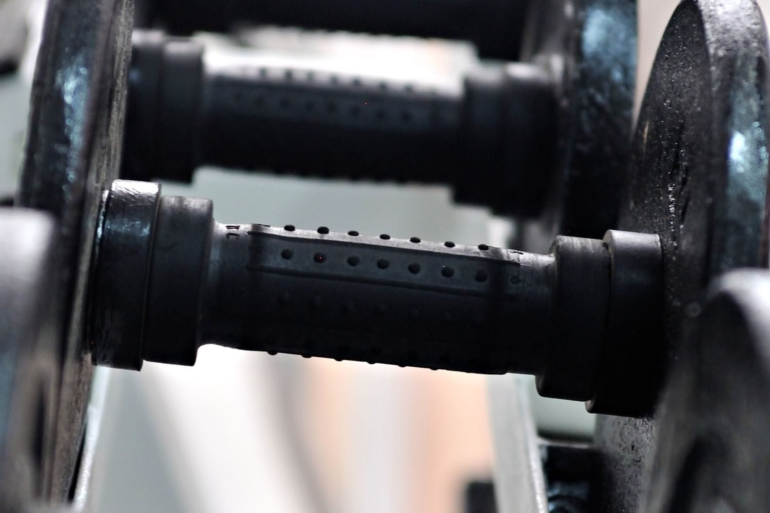 Close-up of black dumbbell handles racked in a gym
