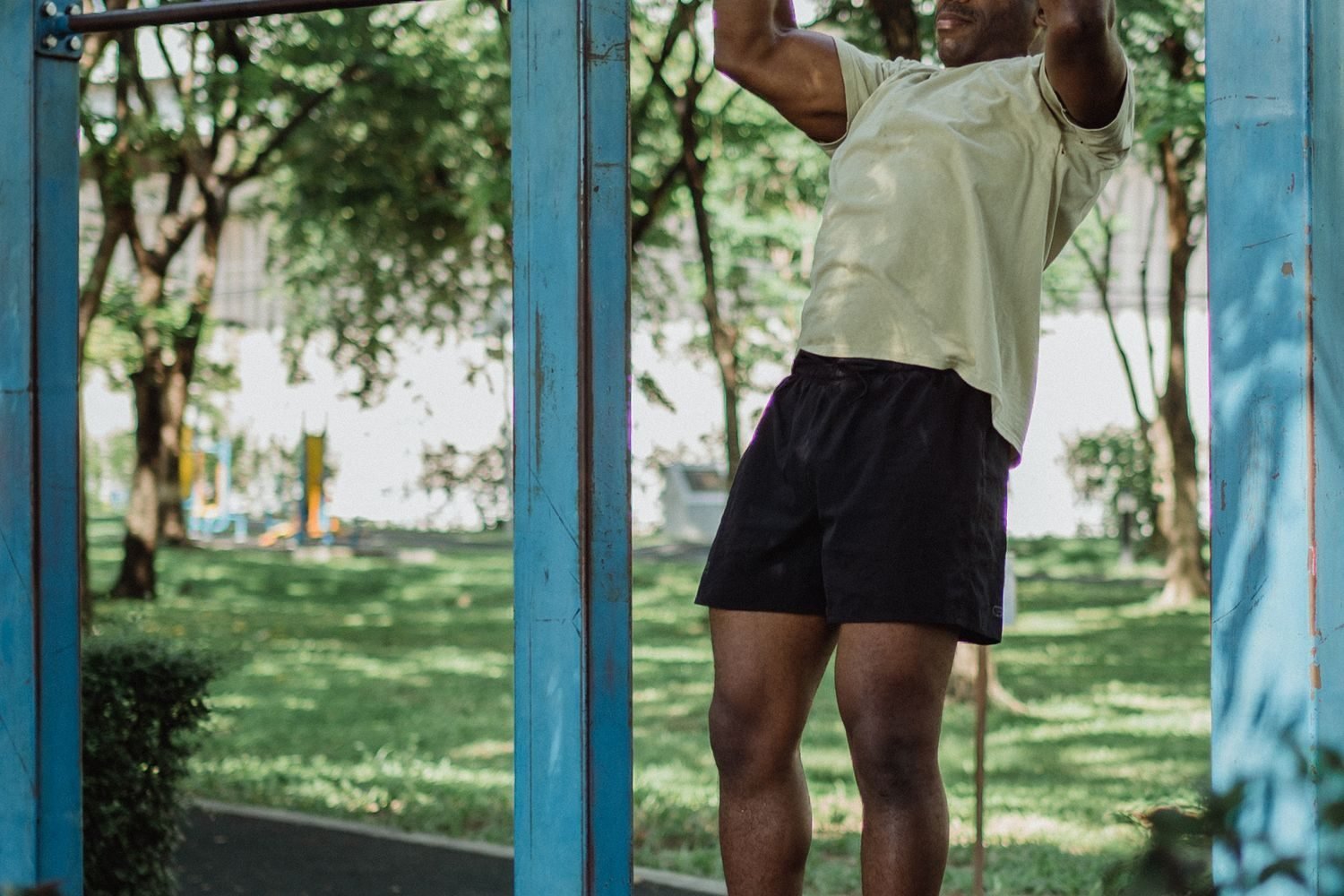 Man performing a pull-up on an outdoor pull-up bar surrounded by trees