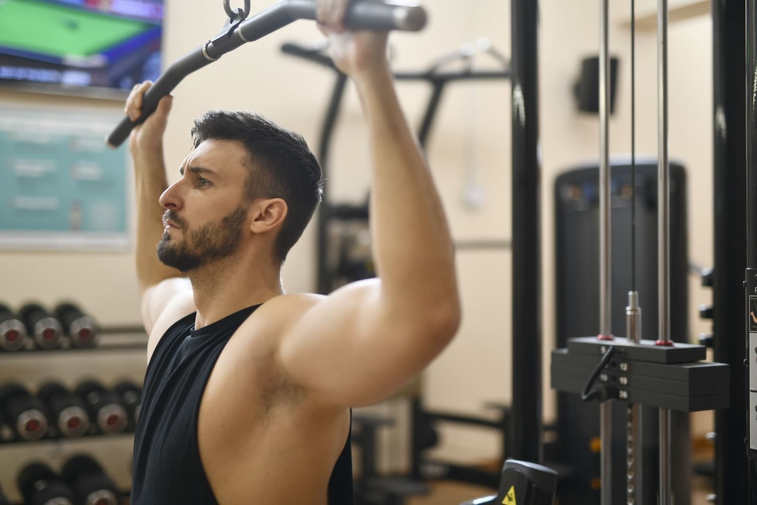 Man performing a lat pulldown machine exercise at the gym
