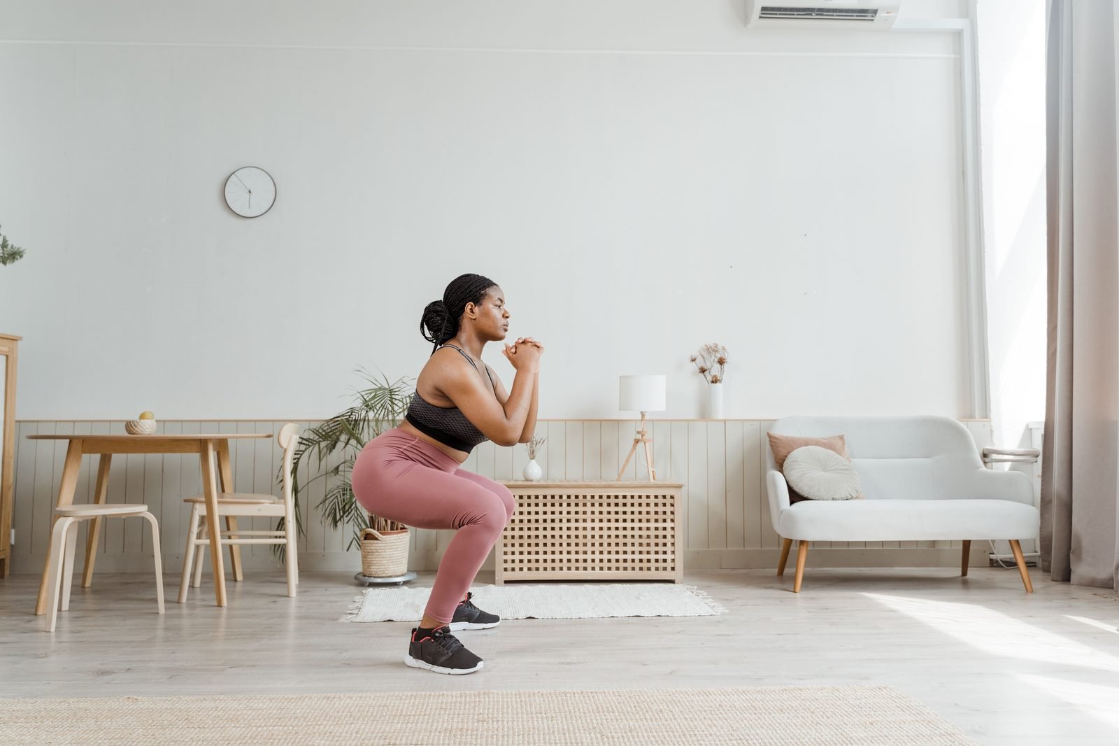 Woman performing a bodyweight squat in her living room for a home leg workout