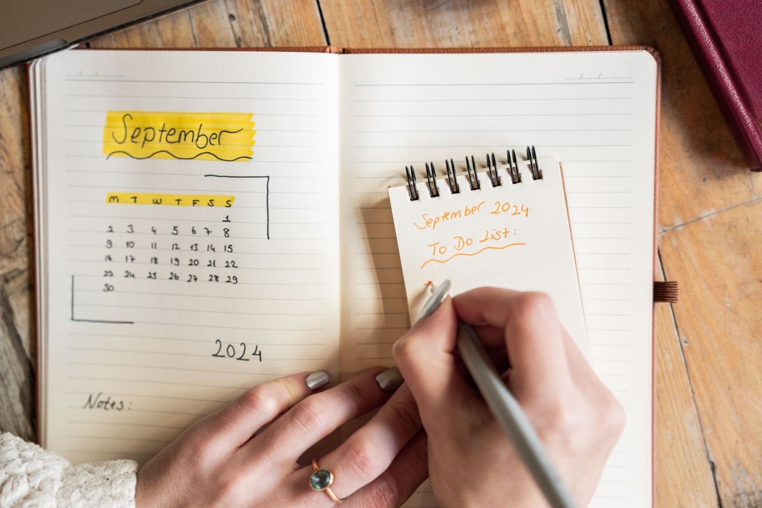 Person writing a to-do list and calendar notes in a notebook