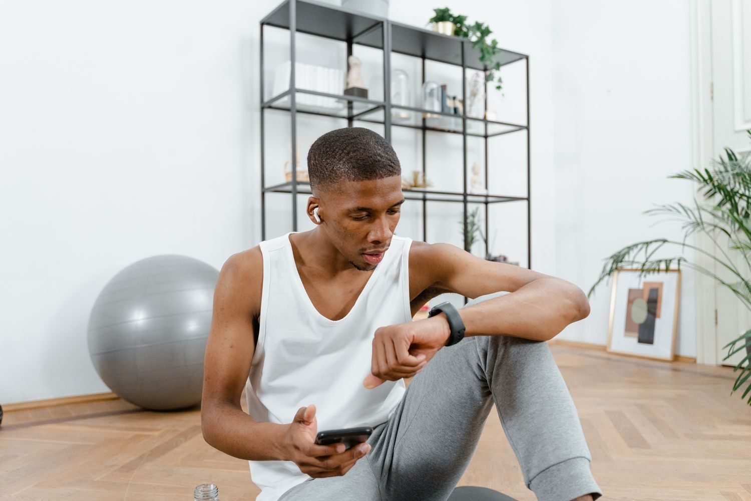 Man checking his watch while planning a workout session at home