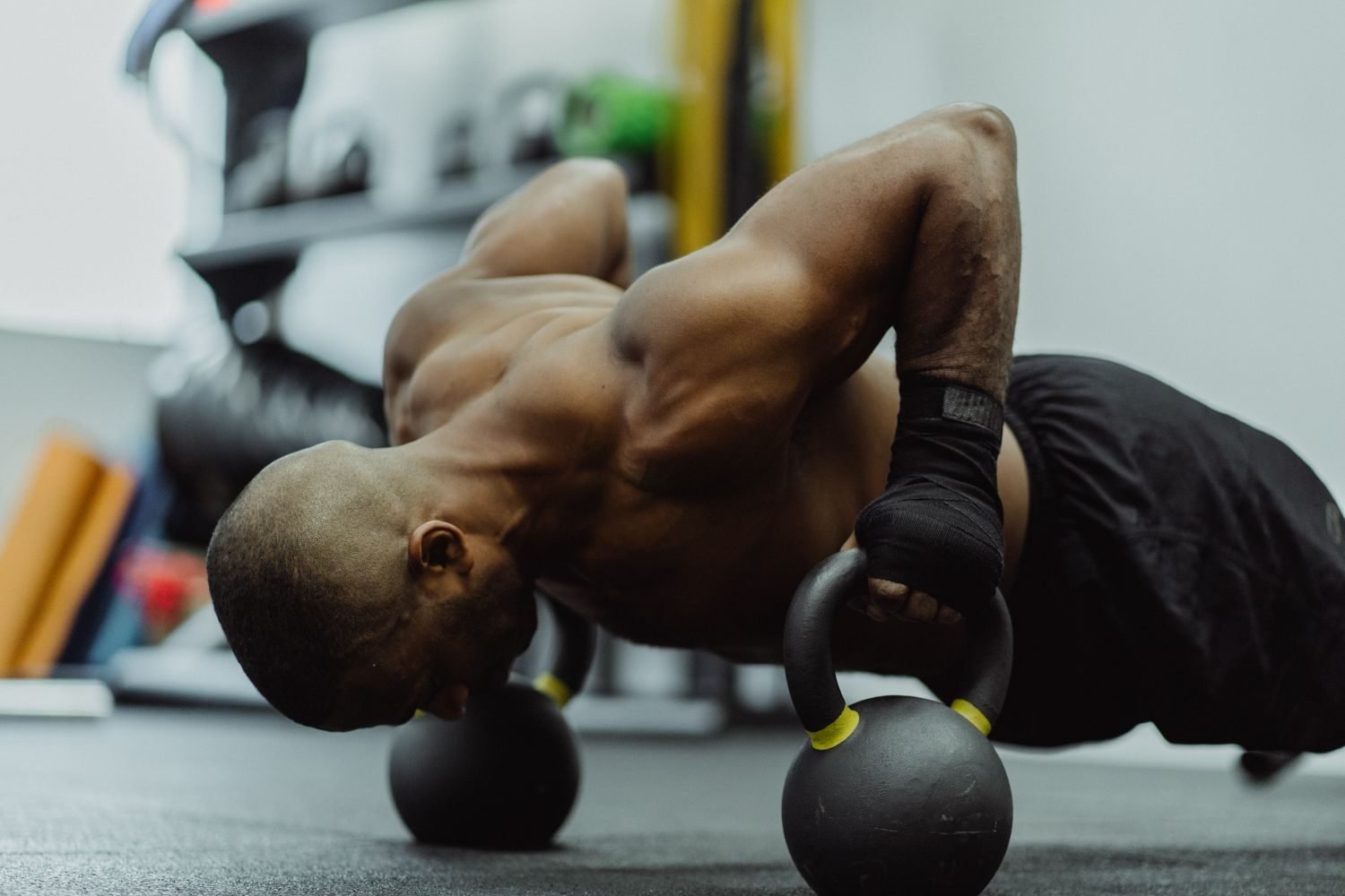 Man performing a push-up using kettlebells as elevated handles during a home workout