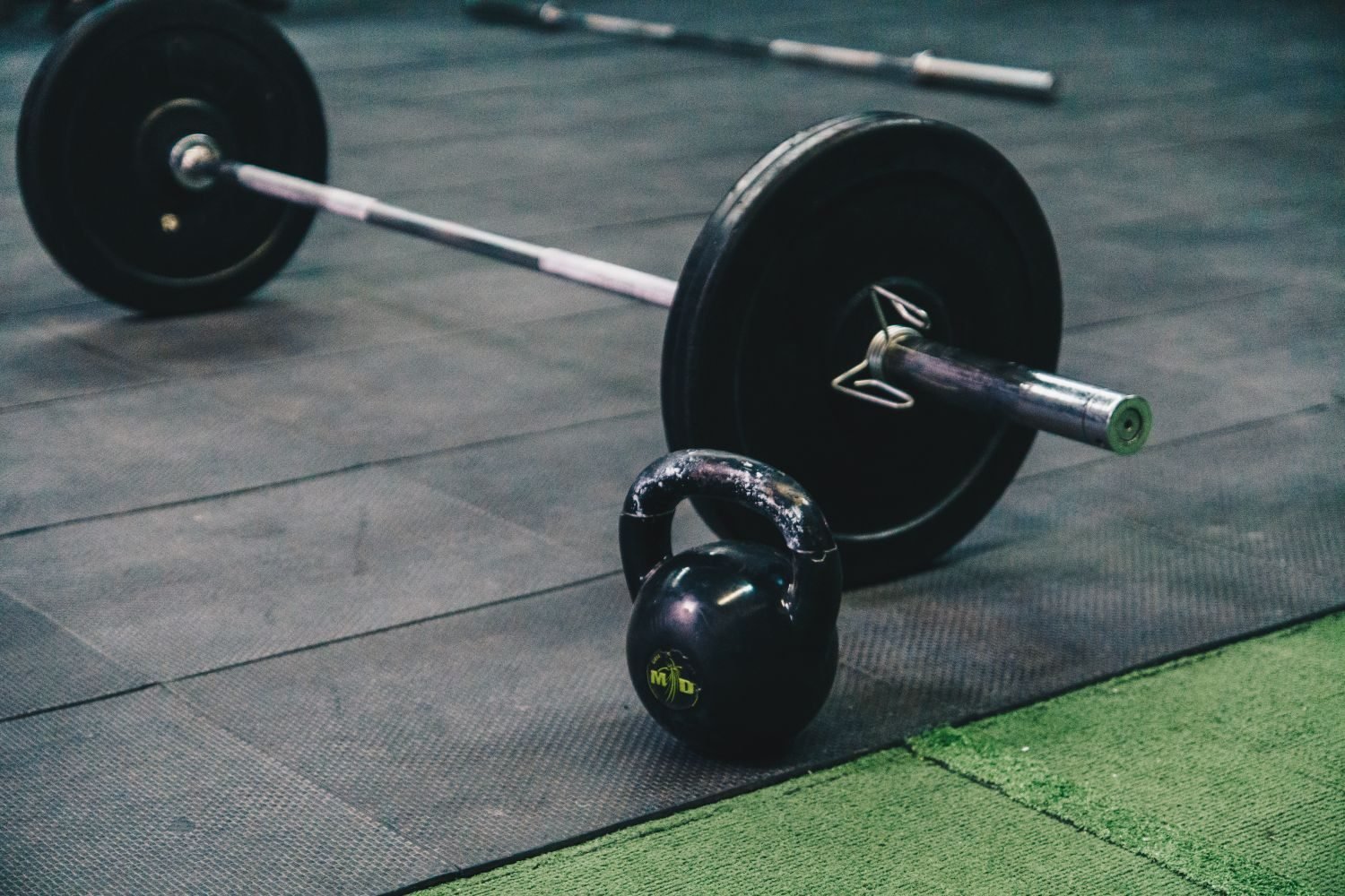 Barbell and kettlebell resting on a gym floor