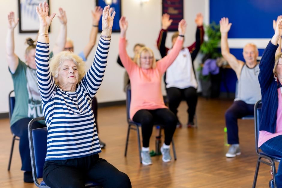 Group of older adults exercising with raised arms in a class